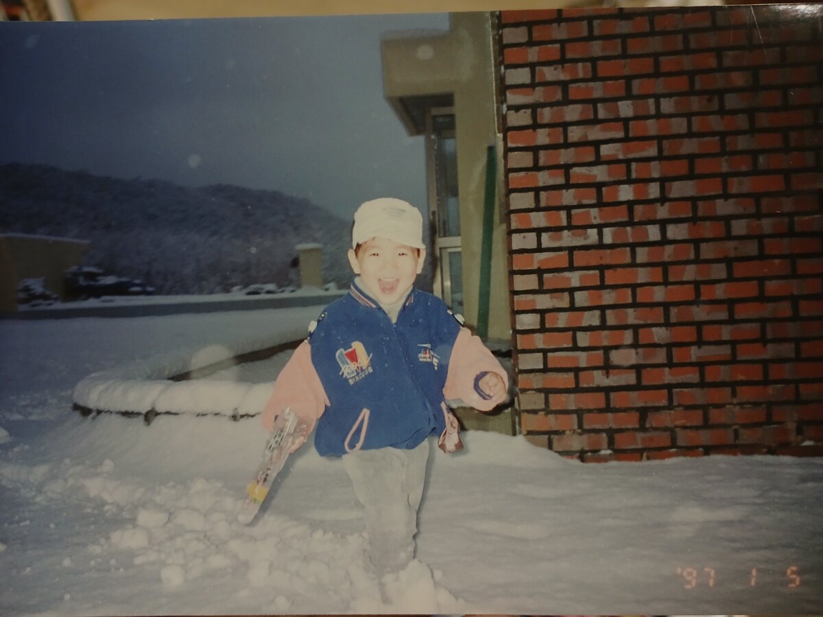 Rok as a kid, grinning in the snow, 1997